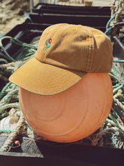 Brown cap with a small embroidered design on a background of ropes and equipment