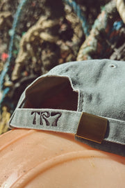 Denim cap with 'TRY7' logo on a pumpkin against a blurred natural background